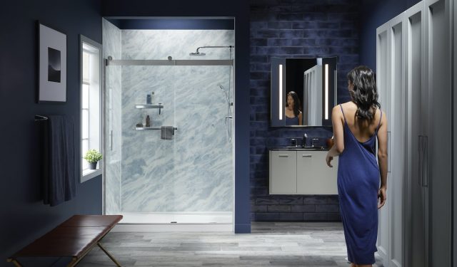 Woman entering bathroom with Bluette LuxStone shower walls'