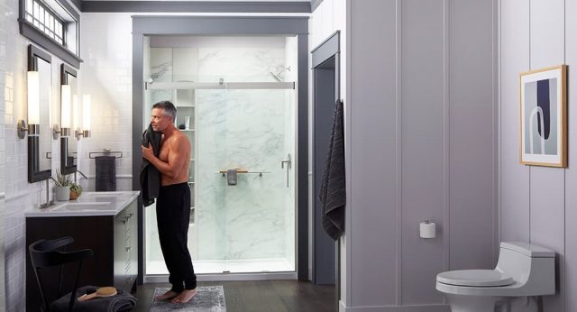 Man drying face with towel at double vanity'