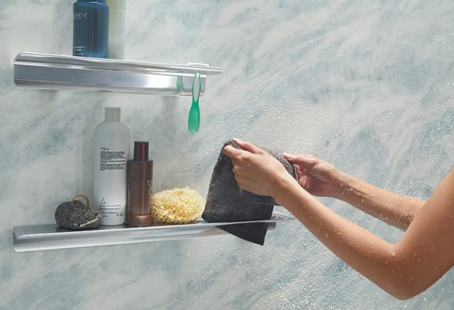 Person draping washcloth on a shelf in the shower