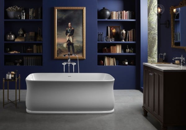 Indigo bathroom with freestanding tub and large portrait overhead.