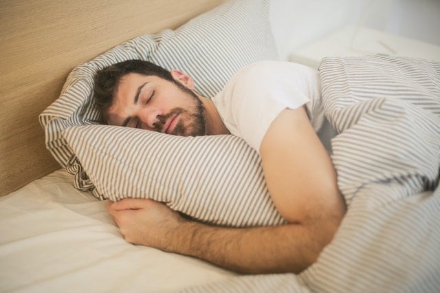 Man sleeping in bed with blanket and pillow