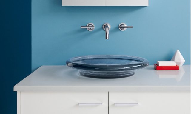 Bathroom sink with blue wall and red soap dispenser