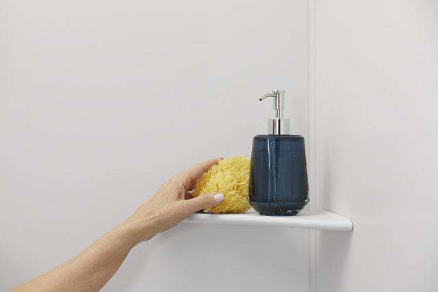 a hand reaching toward a shower shelf