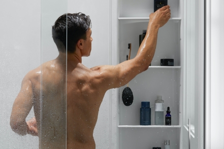 man reaching up to top shelf of shower locker